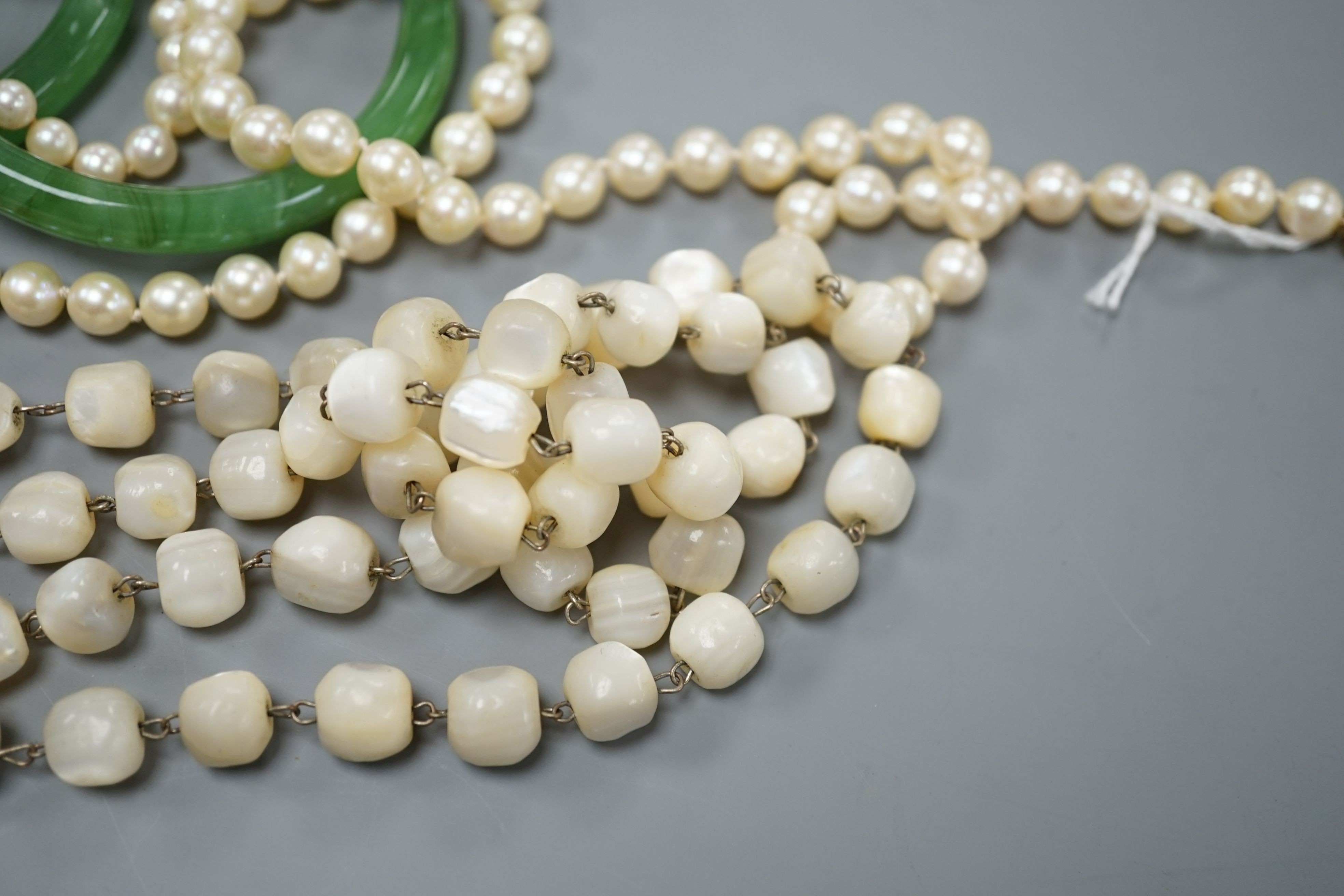 Two single strand cultured pearl necklaces, one with 9ct gold clasp, two green glass bangles, a coral bead necklace and a mother of pearl bead necklace.